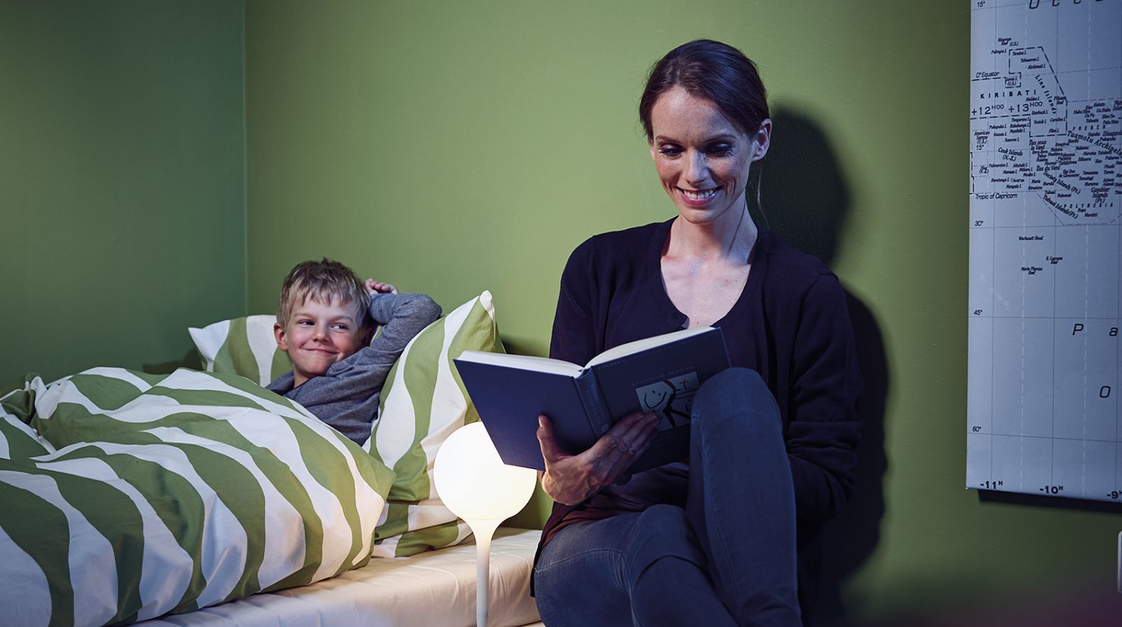 Mutter liest einschlafenden Jungen aus einem Buch vor